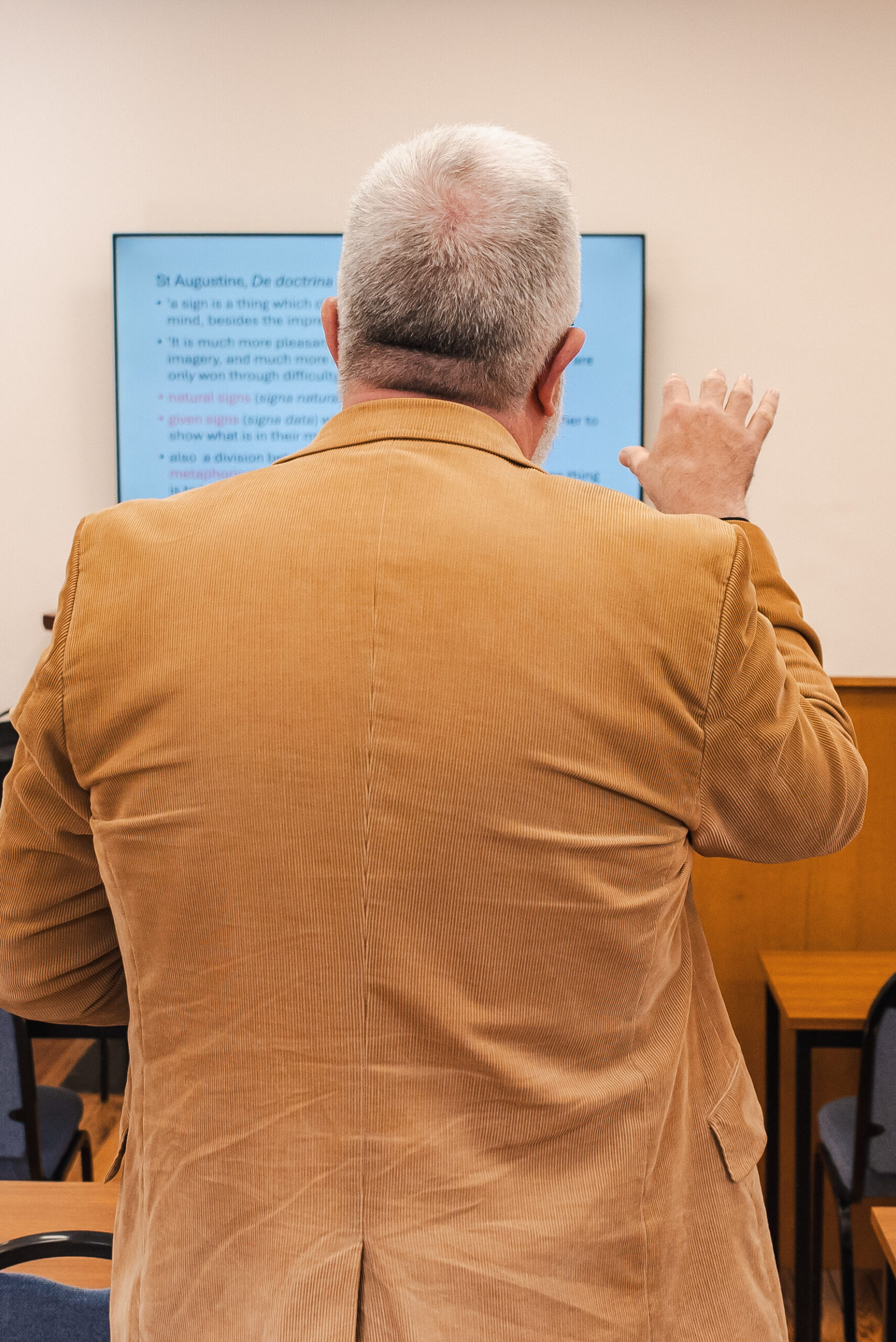 SEI tutor teaching, with back to the camera pointing at powerpoint slide 