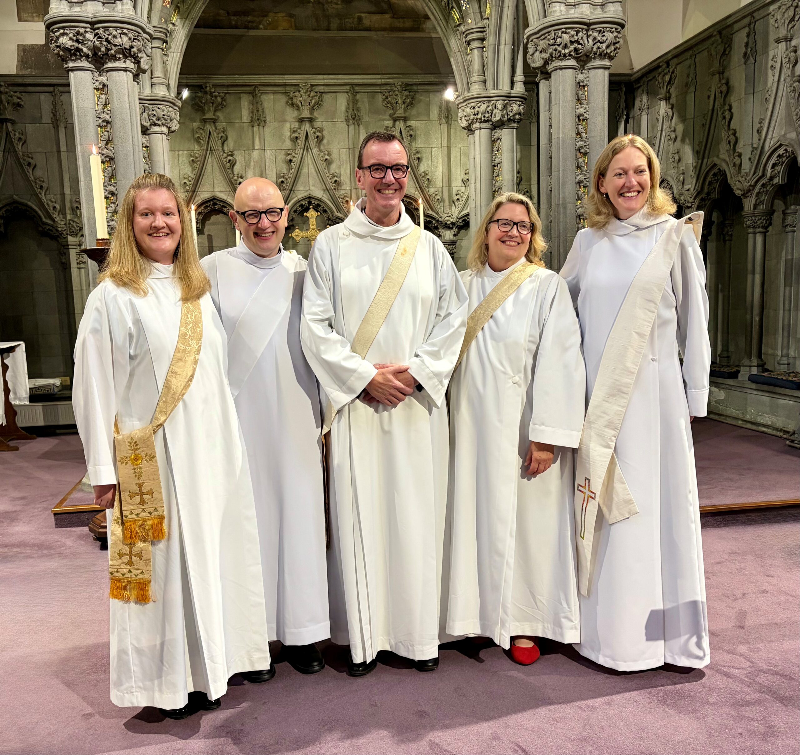 Five newly ordained Deacons standing together and smiling for a photo inside St Ninian's Cathedral, Perth.